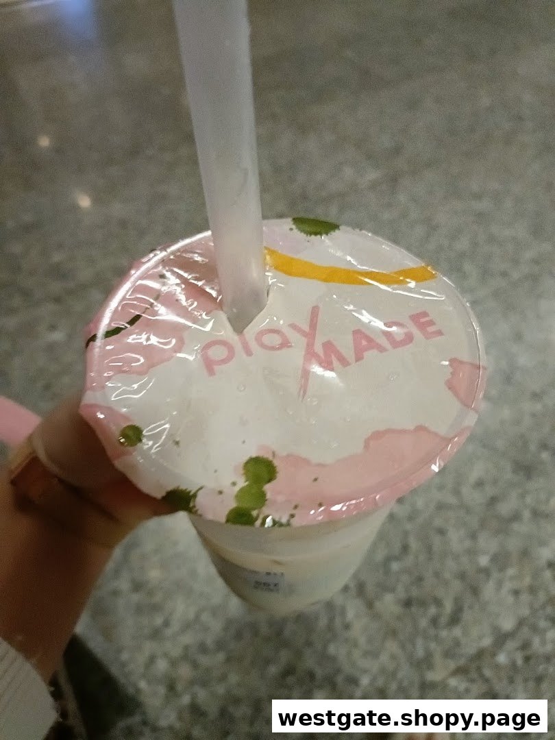 A close-up of a PlayMade bubble tea cup with a straw, featuring its distinctive lid design.