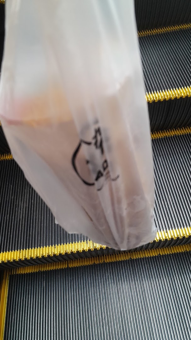 A PlayMade plastic bag with a drink inside, resting on an escalator.