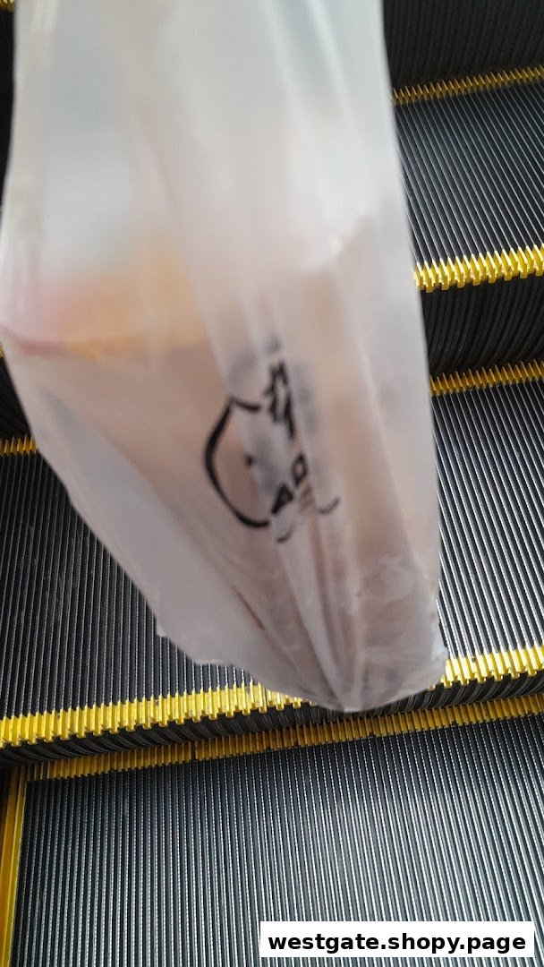 A PlayMade plastic bag with a drink inside, resting on an escalator.
