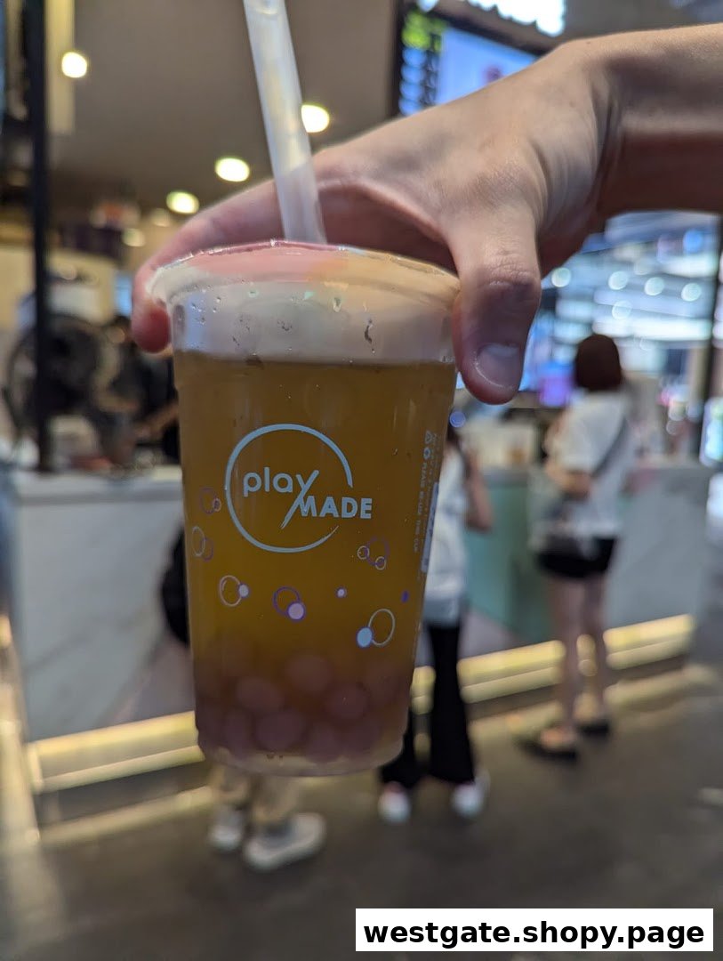 A hand holds a refreshing PlayMade bubble tea drink with purple pearls, showcasing the brand logo.