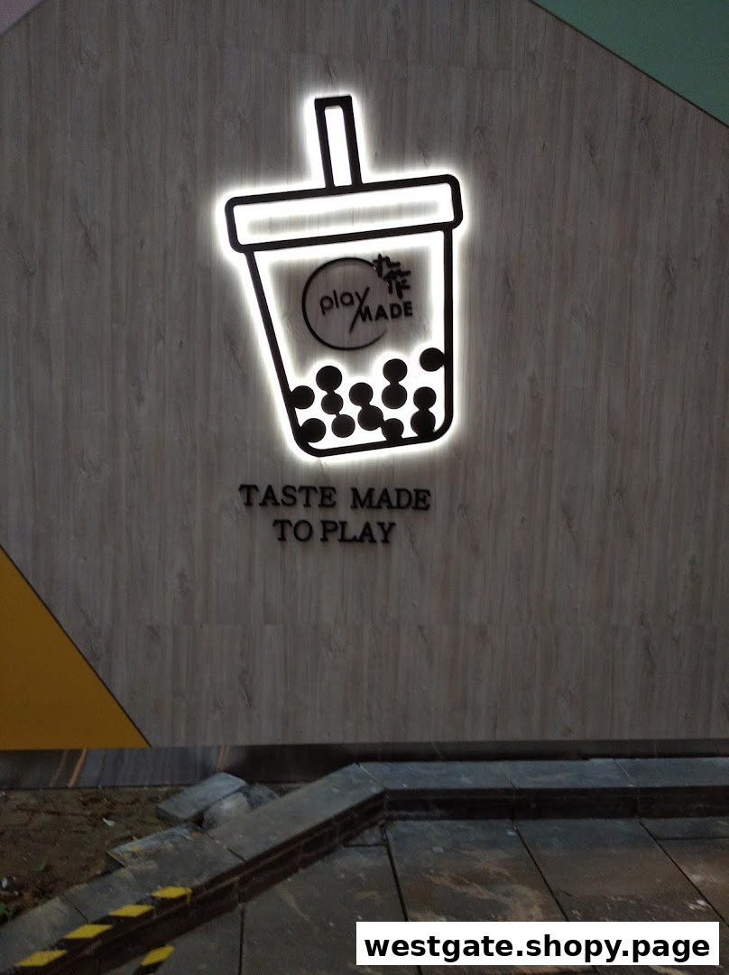 Illuminated PlayMade bubble tea logo and 'Taste Made to Play' slogan on a textured wall.