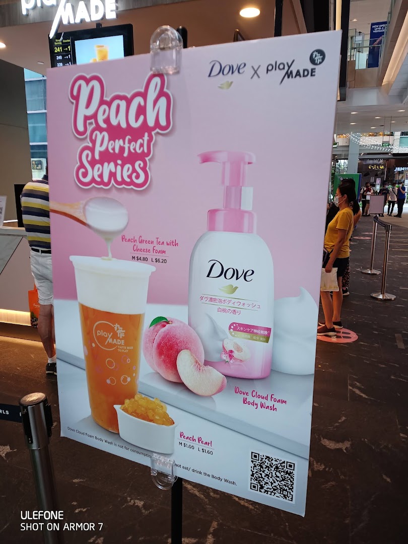 A promotional standee for PlayMade's Peach Perfect Series, featuring a collaboration with Dove.