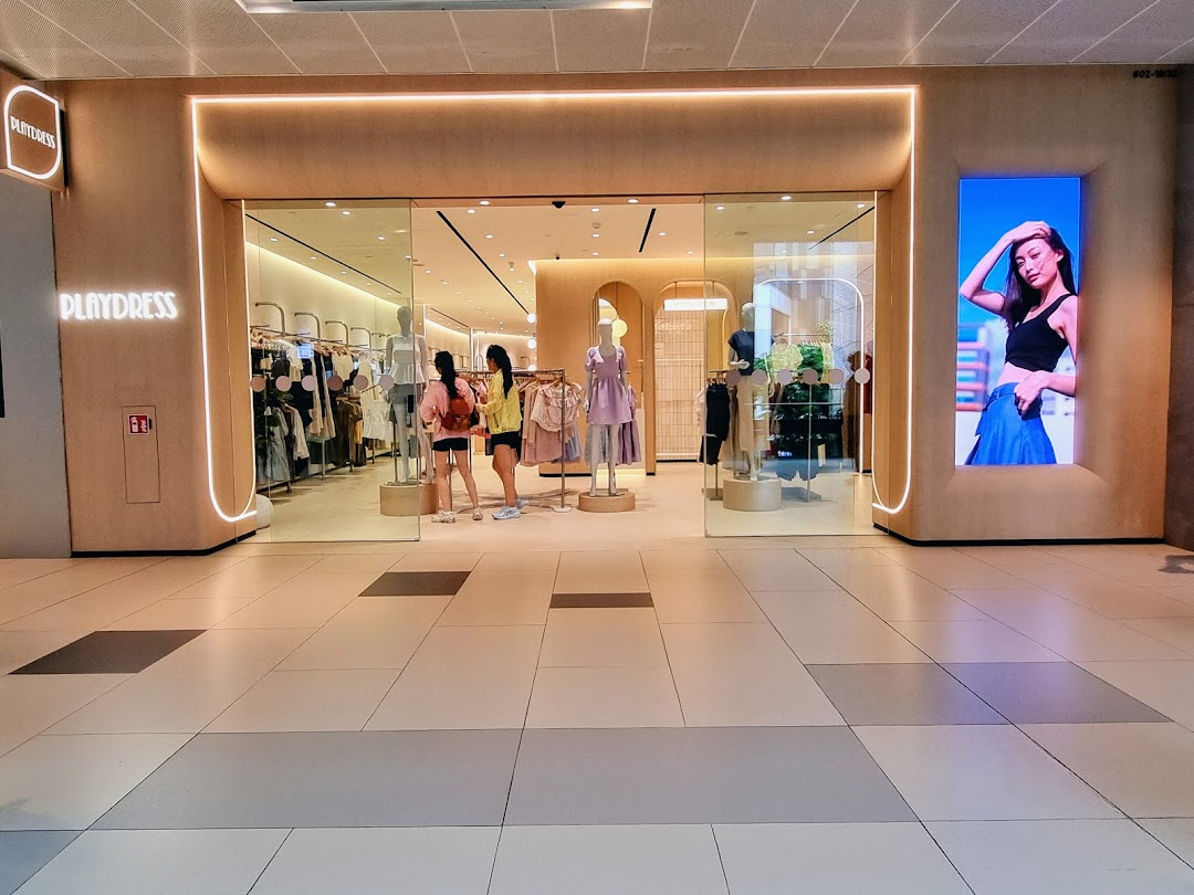 The brightly lit storefront of PLAYDRESS, showcasing modern apparel and inviting customers inside.