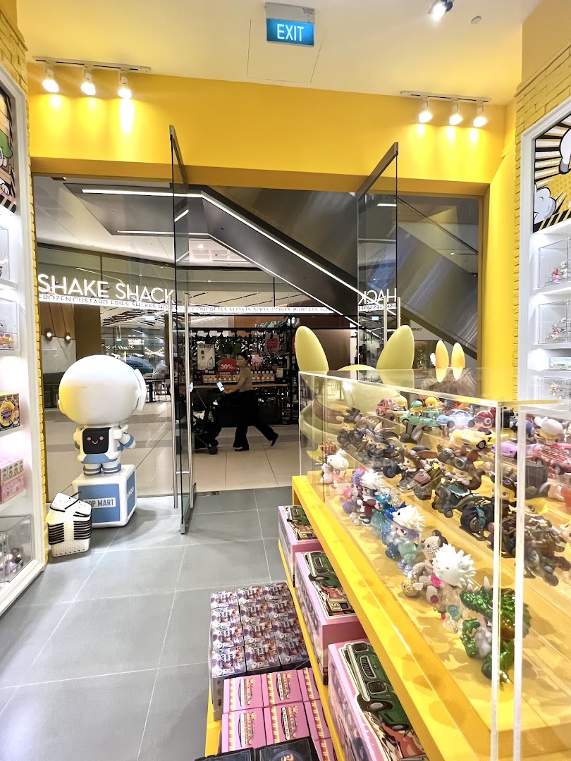 An interior view of POP MART, showcasing collectible figures and a character statue near the entrance.