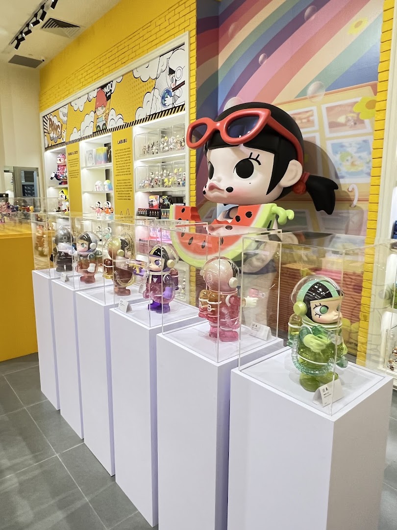 An interior view of POP MART, showcasing colorful collectible art toys on display pedestals with vibrant decor.