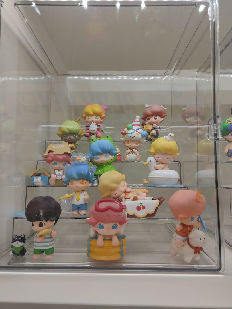 A clear display case showcasing a collection of colorful, stylized collectible figures from POP MART.
