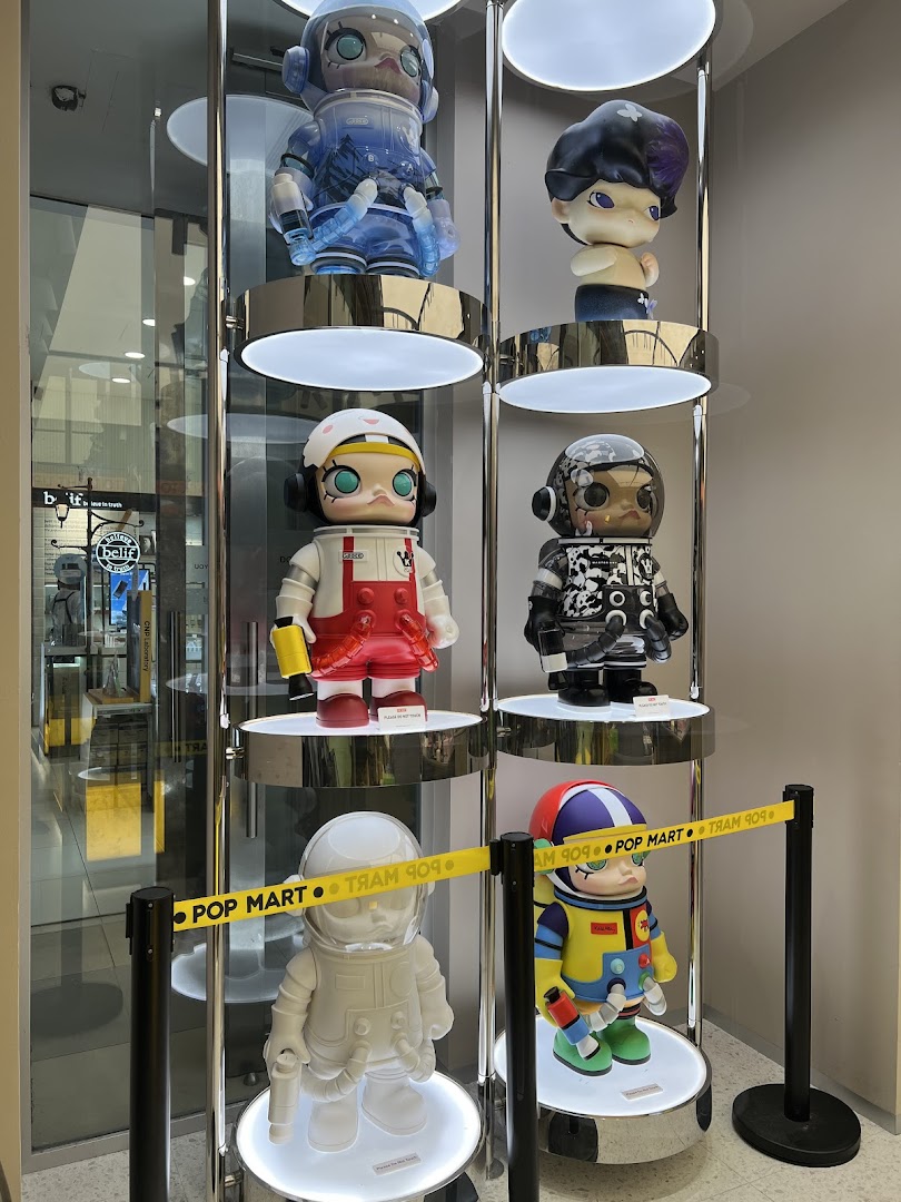 A brightly lit display case showcasing various large, stylized collectible figures from POP MART.