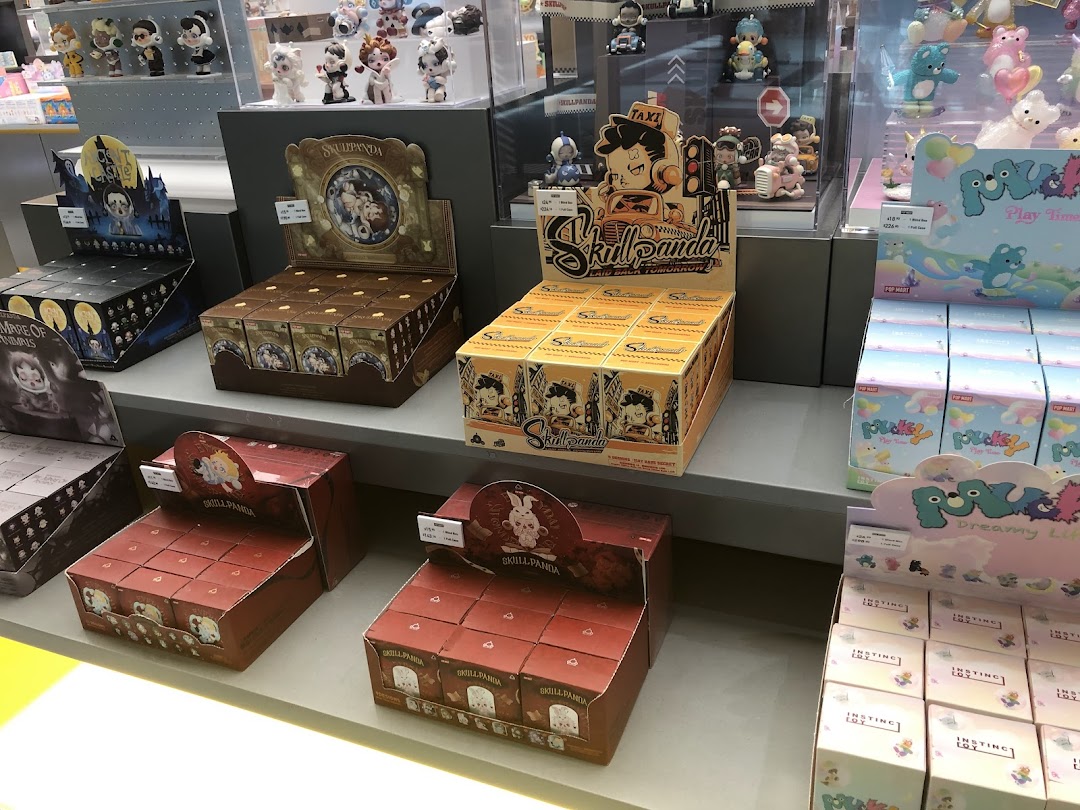Shelves displaying various POP MART blind boxes and collectible figures, including Skullpanda and Pucky series.