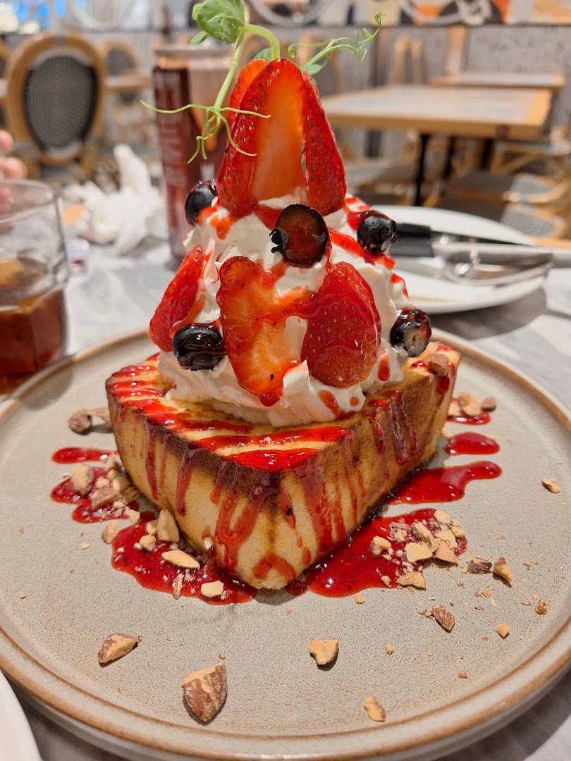 A delicious dessert featuring thick toast topped with whipped cream, fresh strawberries, blueberries, and strawberry sauce.