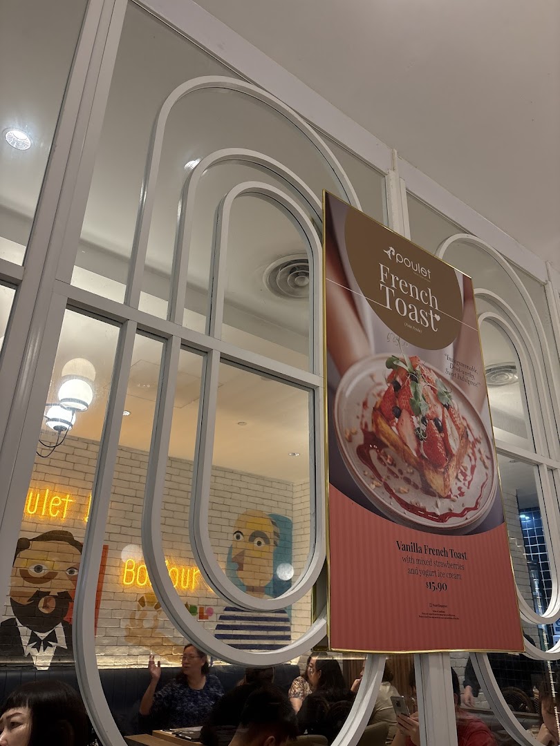 An interior view of Poulet restaurant featuring a promotional poster for Vanilla French Toast and customers dining.
