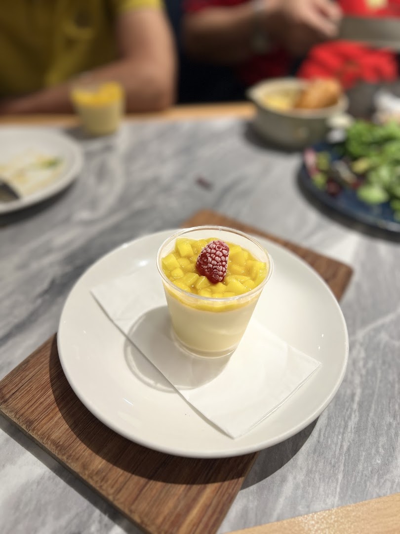 A delightful mango panna cotta dessert with a raspberry garnish served on a white plate.