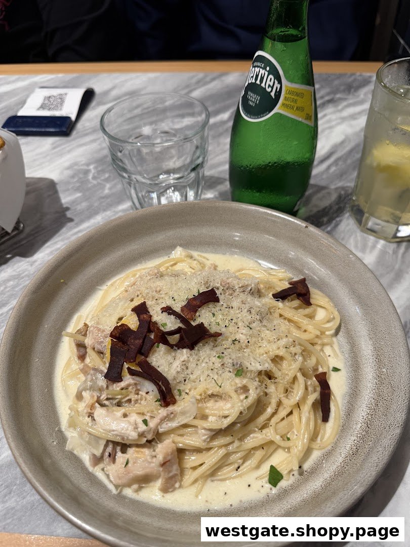 A creamy pasta dish with chicken and crispy toppings, served with Perrier and a refreshing drink.