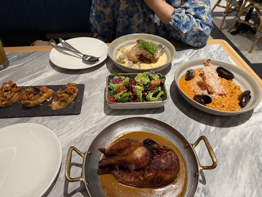 A table laden with various dishes including roasted chicken, seafood risotto, bruschetta, and a fresh salad.