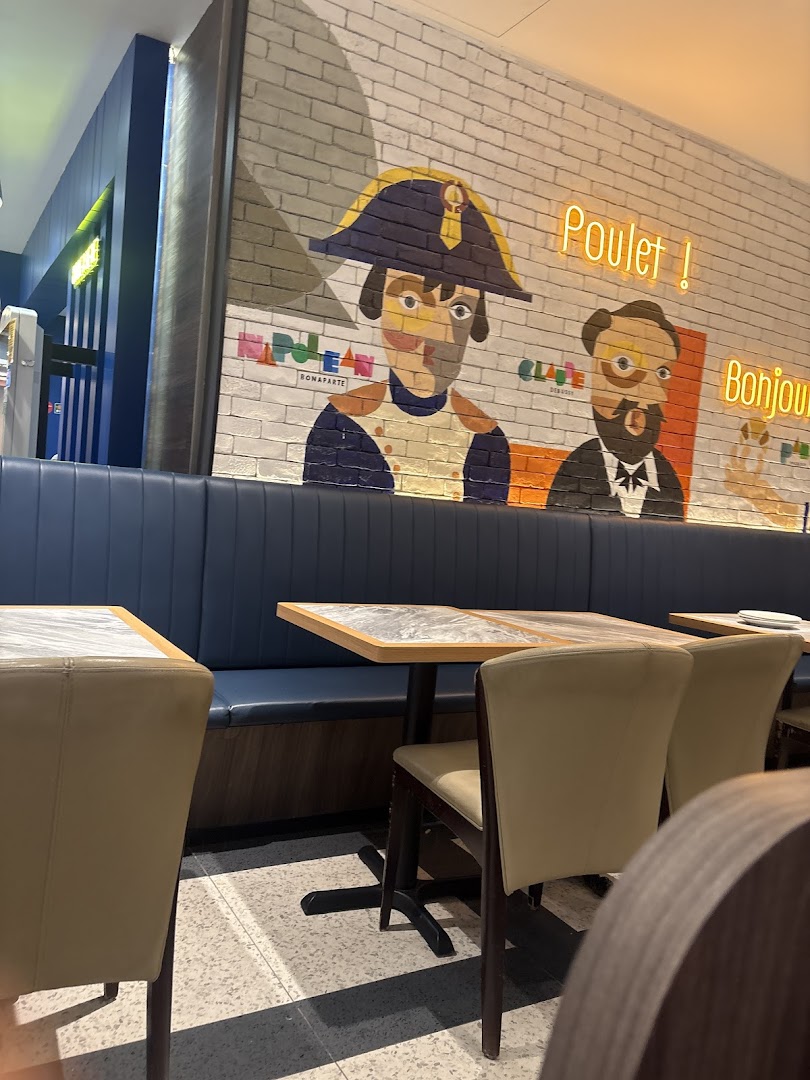 An inviting interior shot of Poulet - Westgate, featuring comfortable booth seating, tables, and a vibrant brick wall mural.