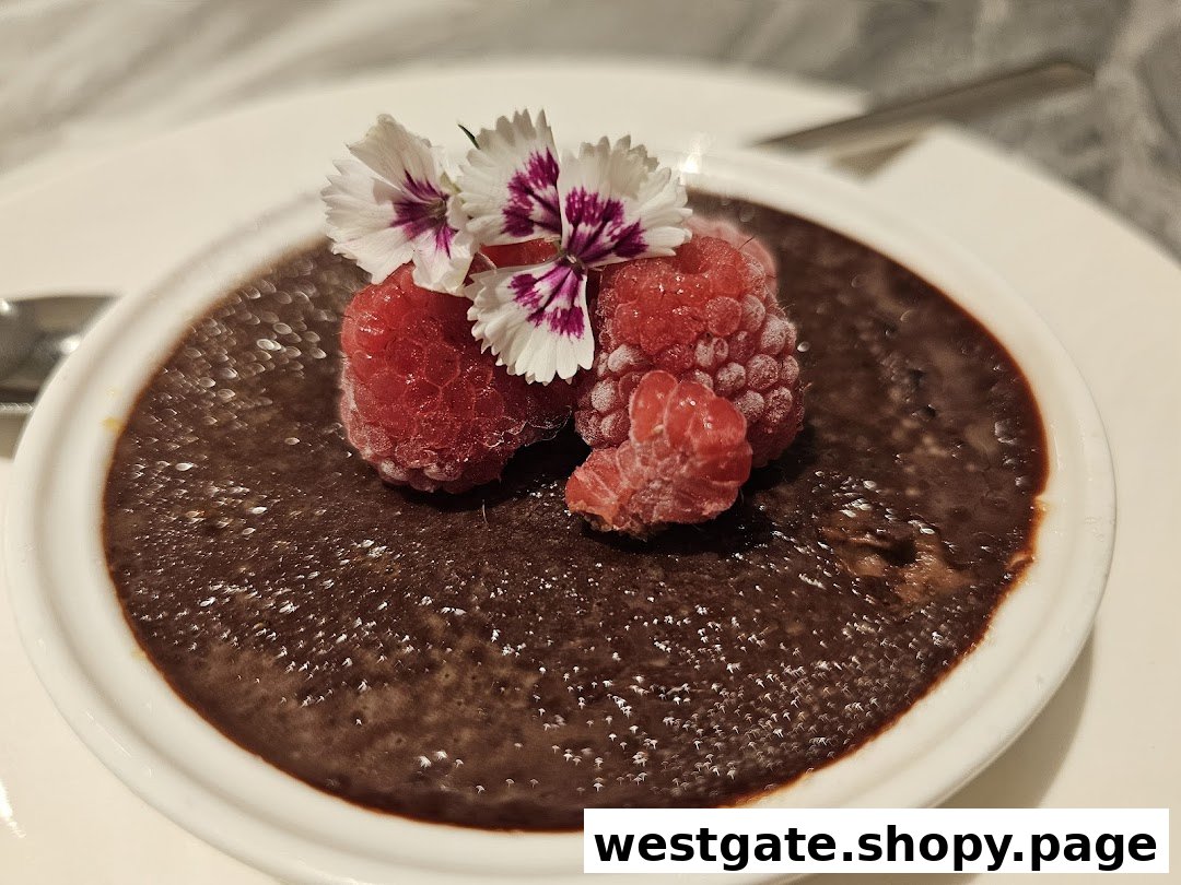 A rich chocolate dessert garnished with fresh raspberries and delicate edible flowers, served in a white ramekin.