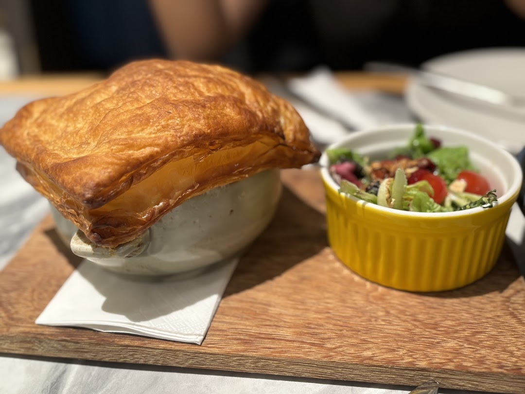 A golden-crusted pot pie and fresh side salad served on a wooden board.