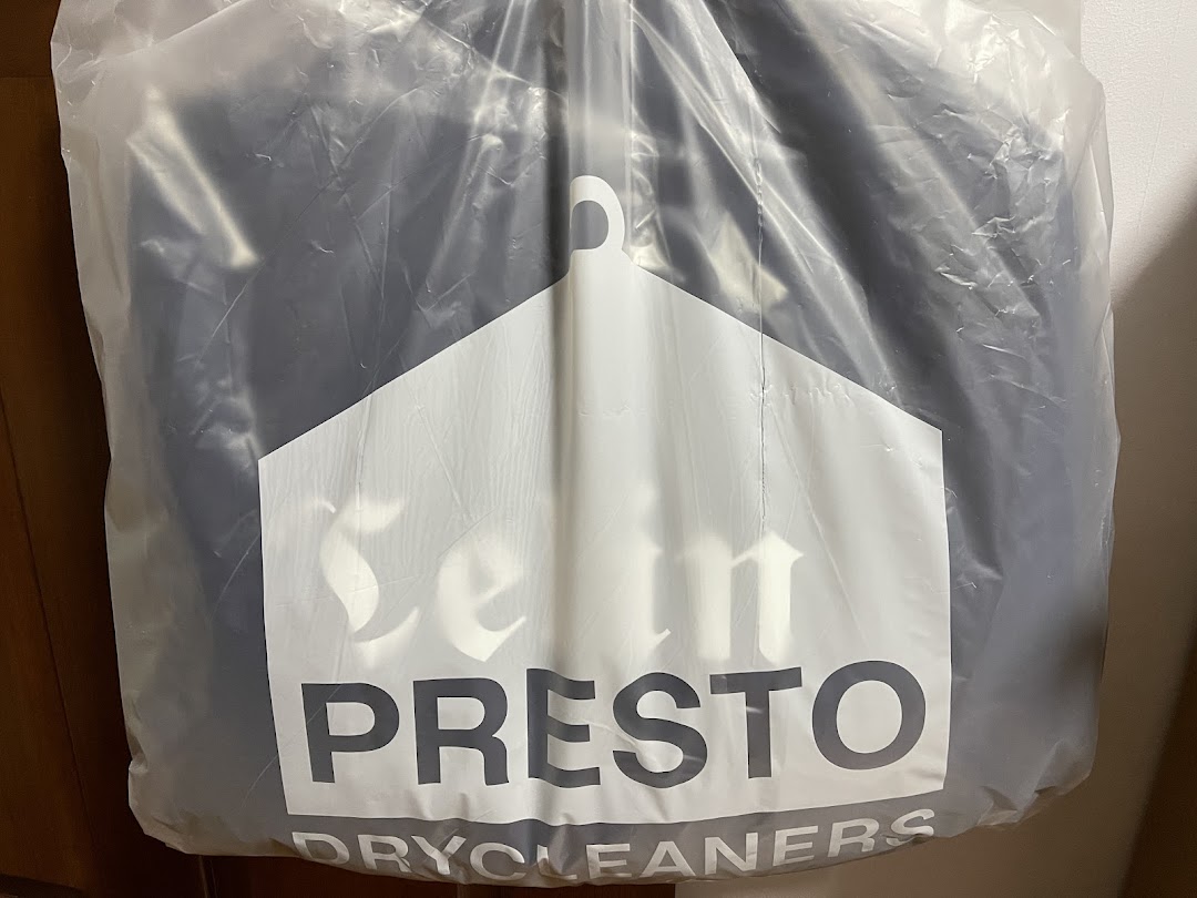 A dry-cleaned garment in a clear plastic bag featuring the Presto Drycleaners logo.