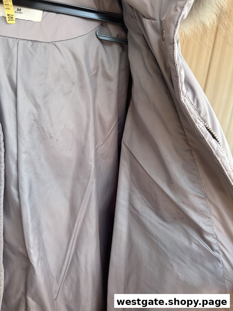 Close-up of the inside of a light-colored coat, likely after professional dry cleaning, with a tag visible.