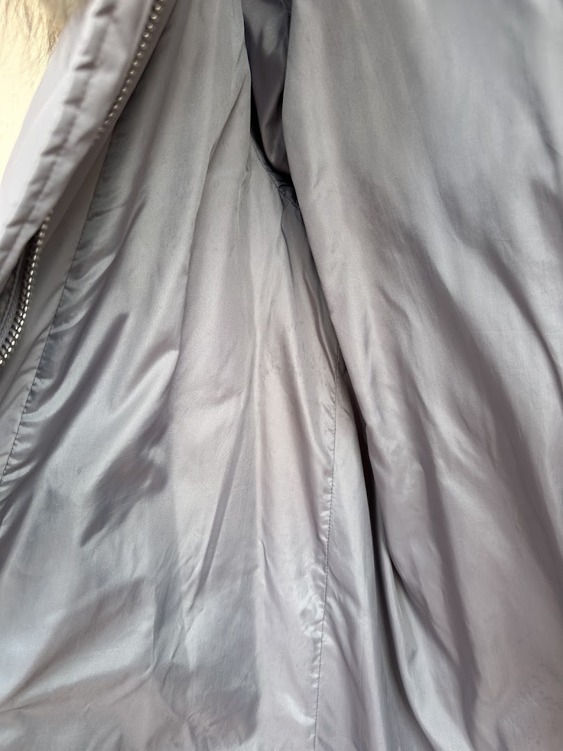 Close-up of the grey interior lining of a garment, possibly a jacket, with a zipper.