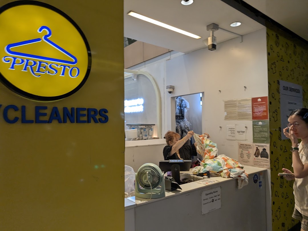 Presto Drycleaners' reception area with staff assisting a customer and the shop's prominent logo.