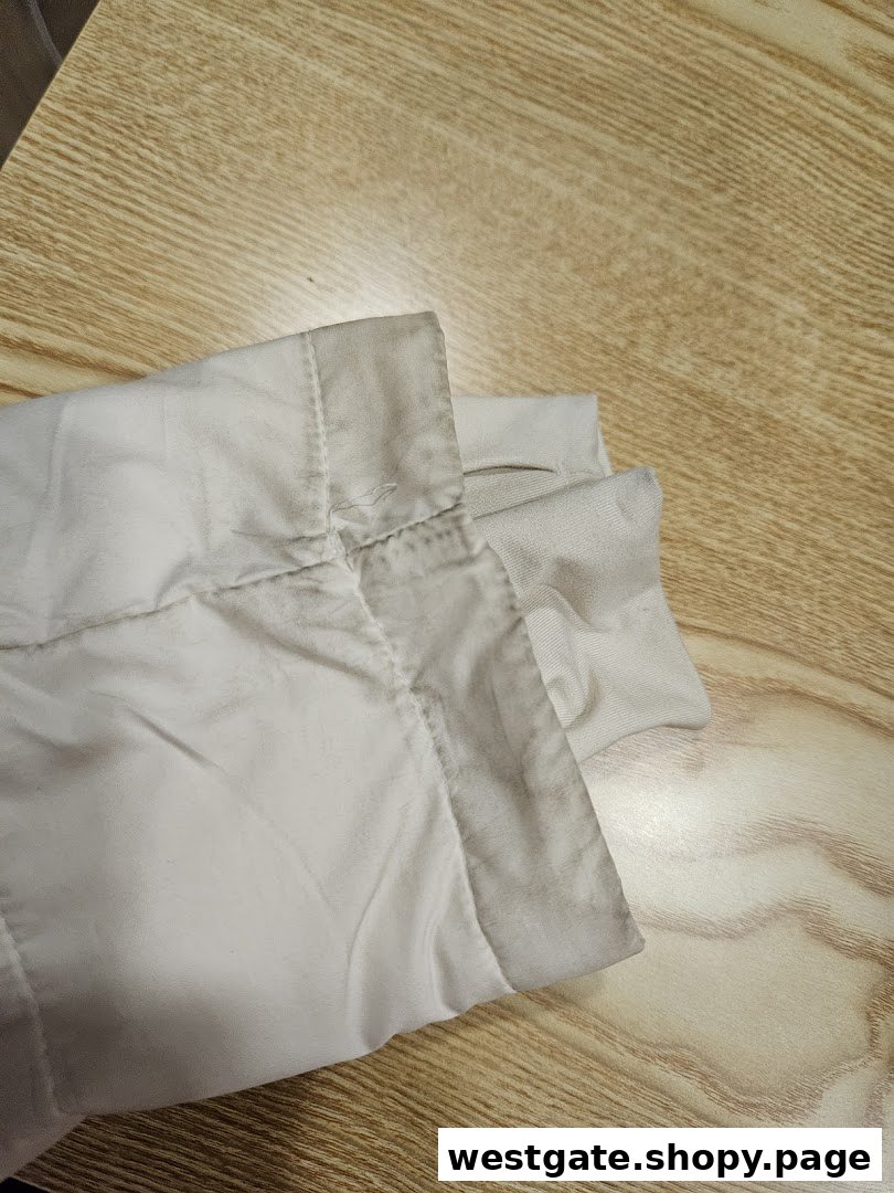 Close-up of a dirty, light-colored garment sleeve on a wooden surface, showing wear and stains.