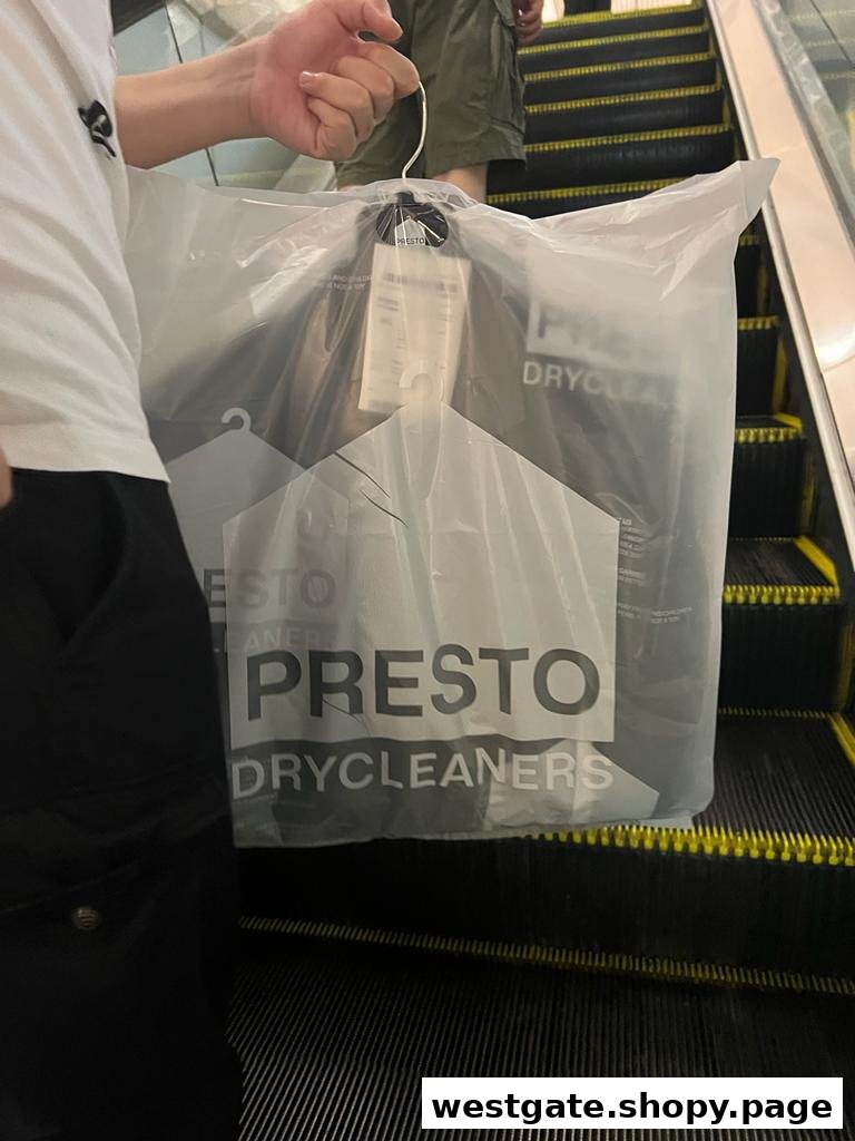 A person carries a freshly dry-cleaned garment in a Presto Drycleaners bag on an escalator.
