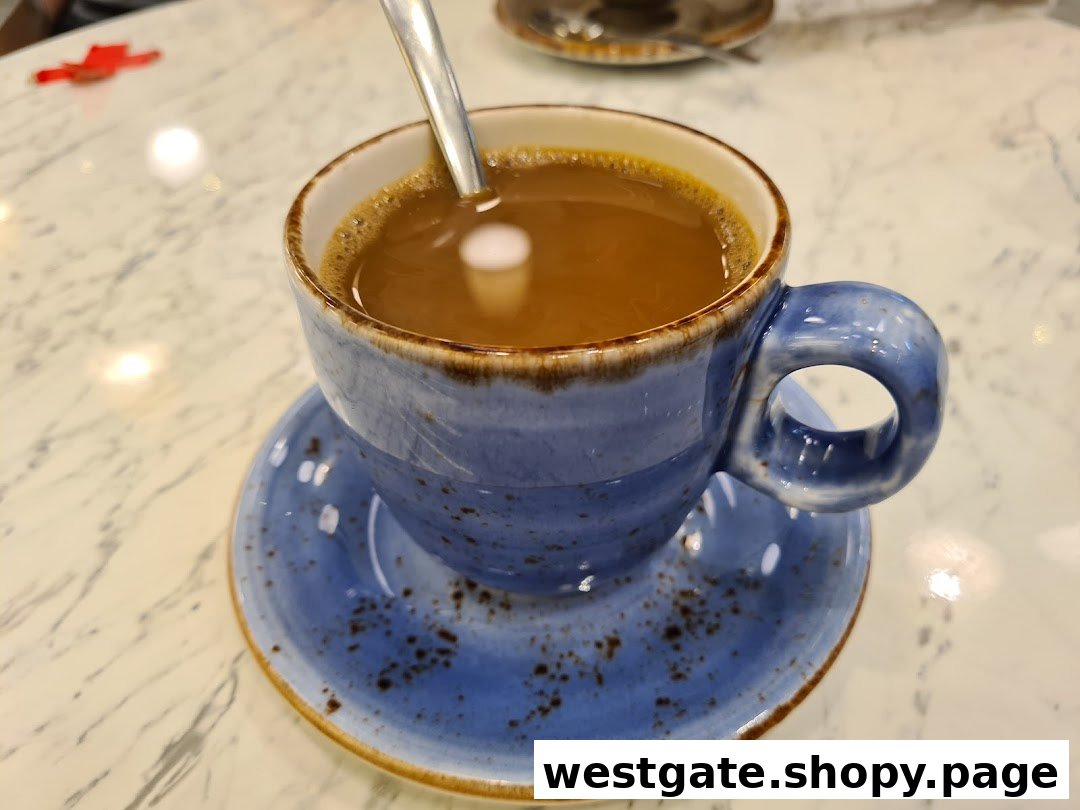 A blue ceramic cup of coffee with a spoon on a white marble table.