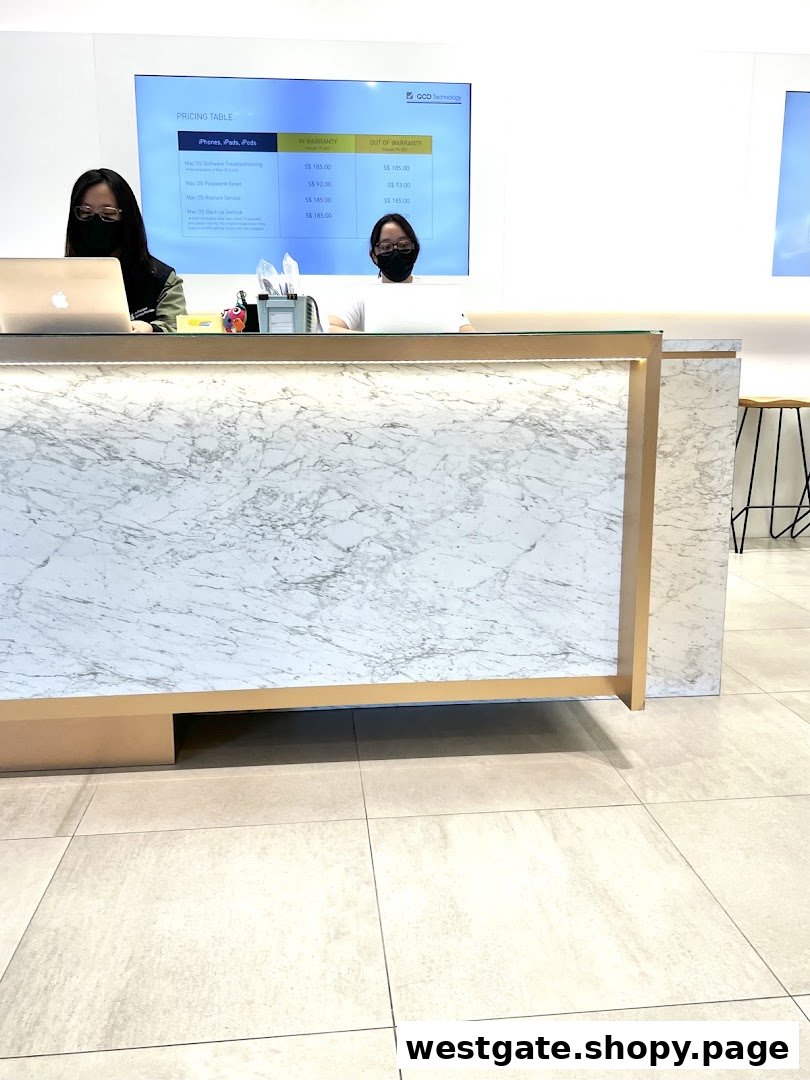 Staff at a modern service counter with a digital pricing table for Apple device repairs.