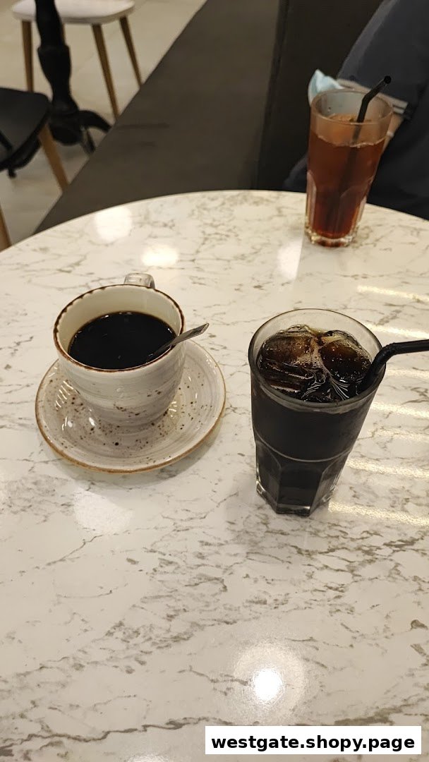 Two drinks, one hot coffee and one iced coffee, on a white marble-patterned table.
