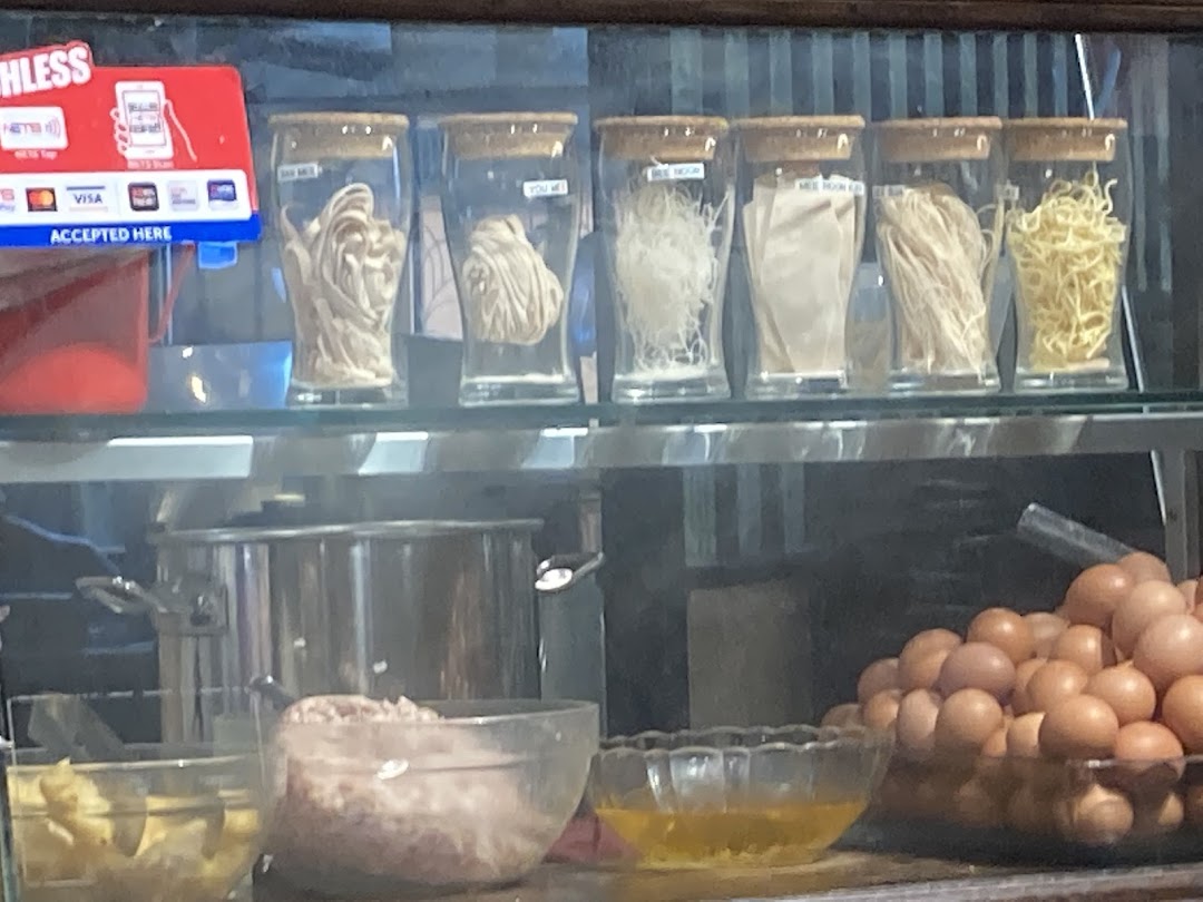 Various fresh noodles, eggs, and ingredients displayed behind the counter at Qiu Lian Ban Mian.