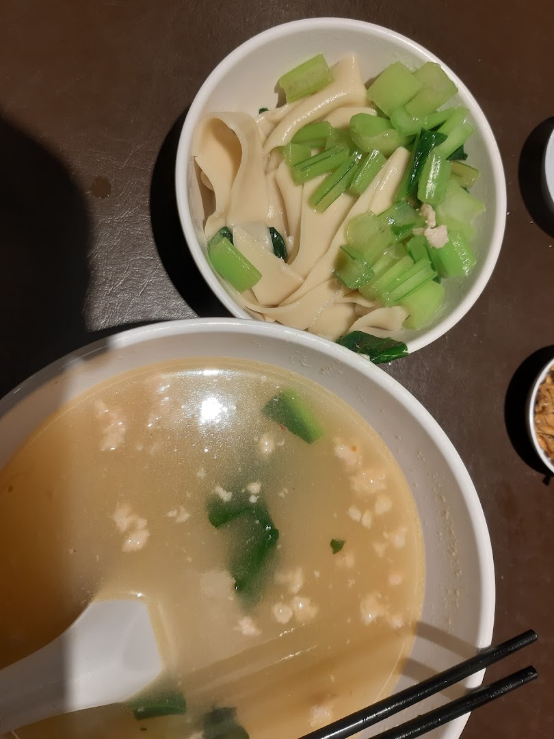 Two bowls of traditional Ban Mian, one with noodles and greens, the other with a rich broth.