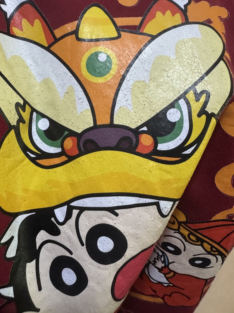Close-up of a vibrant graphic print featuring a lion dance head and cartoon characters on fabric.