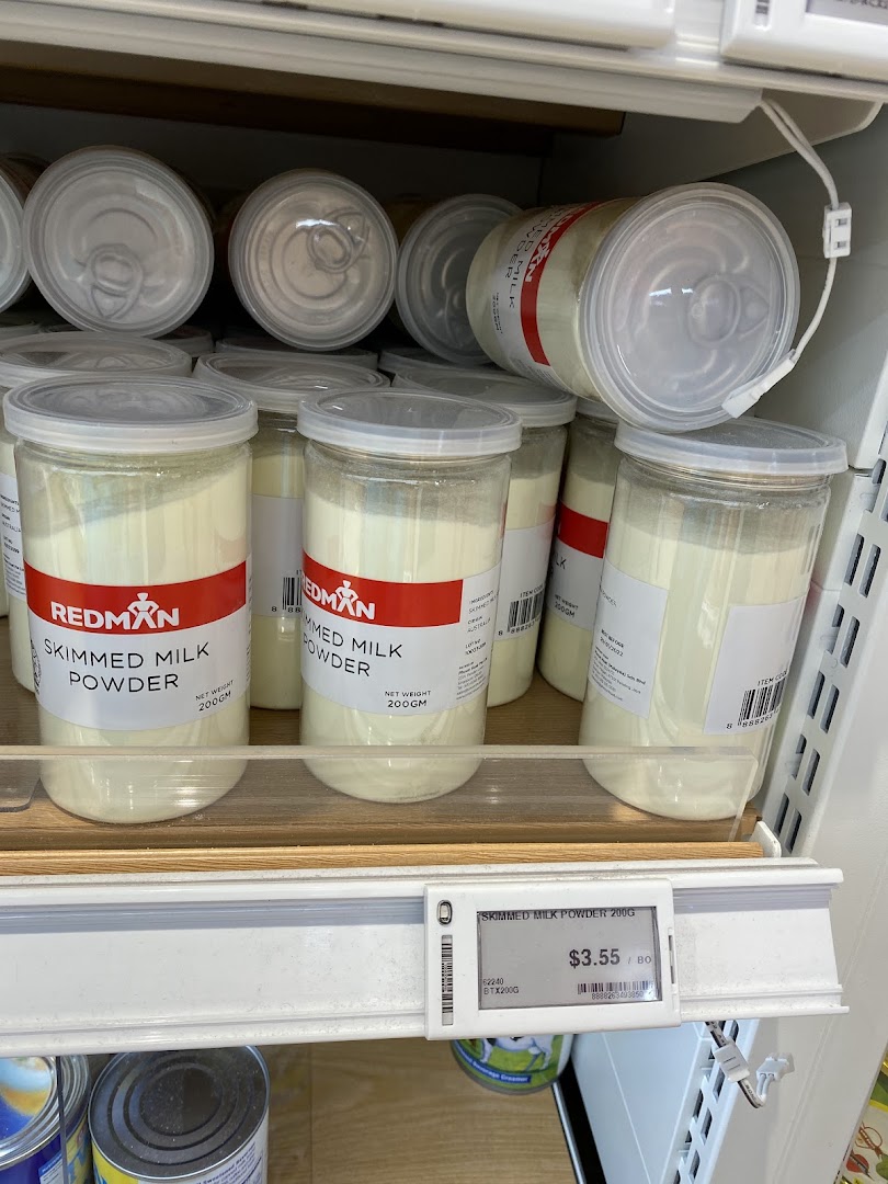 A shelf display of RedMan Skimmed Milk Powder containers with a visible price tag.