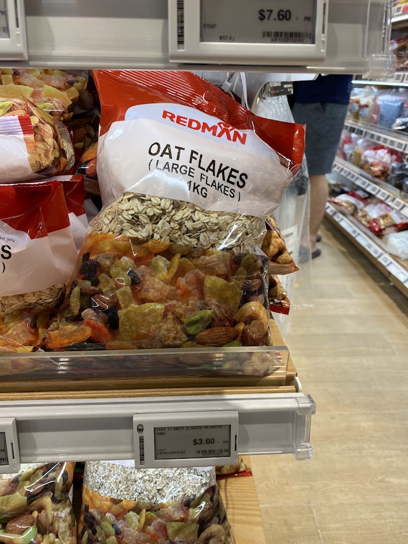 Bags of RedMan Oat Flakes and other dried goods on display in a retail store.