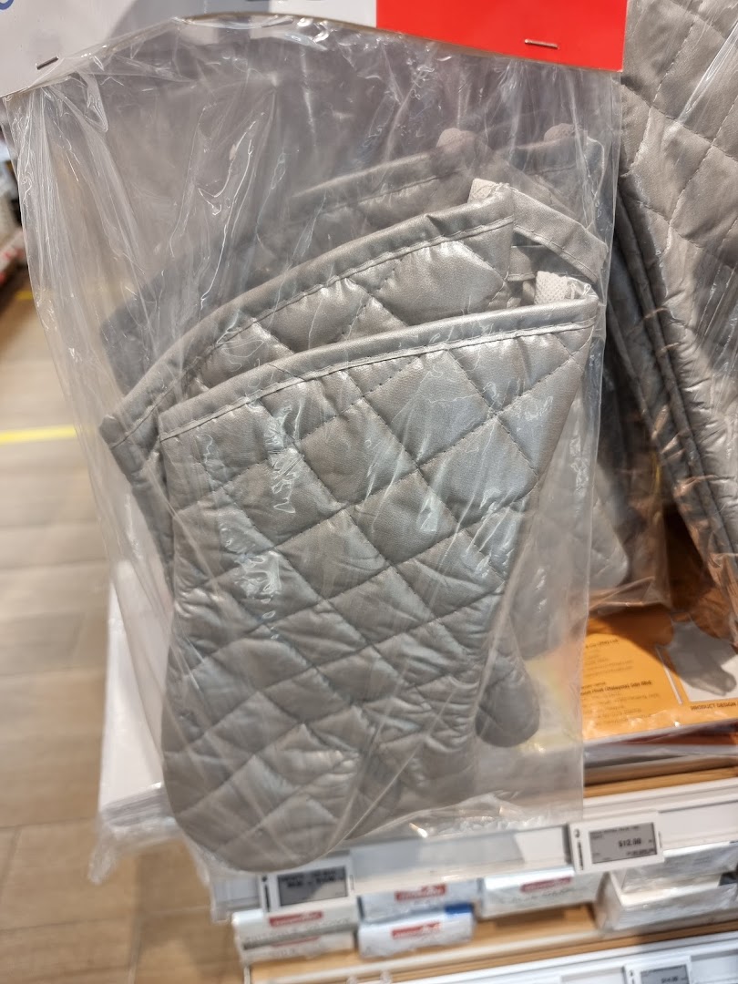 Close-up of quilted silver oven mitts displayed in clear plastic packaging.