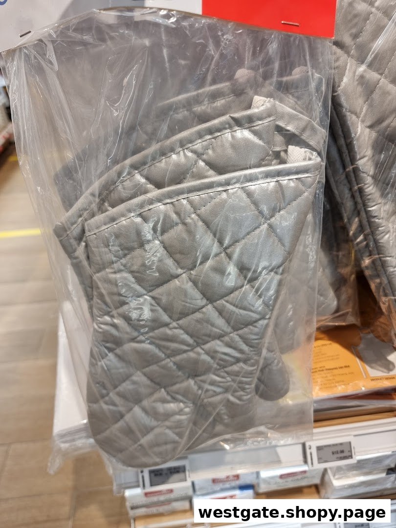 Close-up of quilted silver oven mitts displayed in clear plastic packaging.