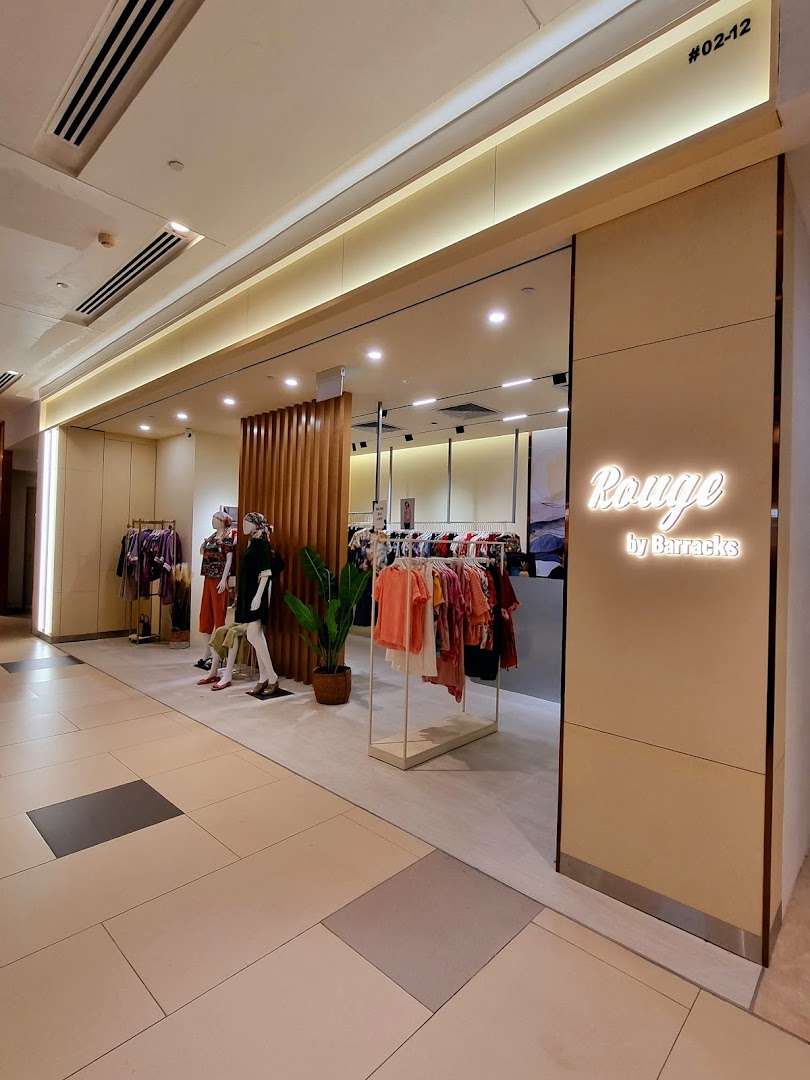 The shopfront of Rouge by Barracks, featuring clothing displays, mannequins, and a glowing sign.
