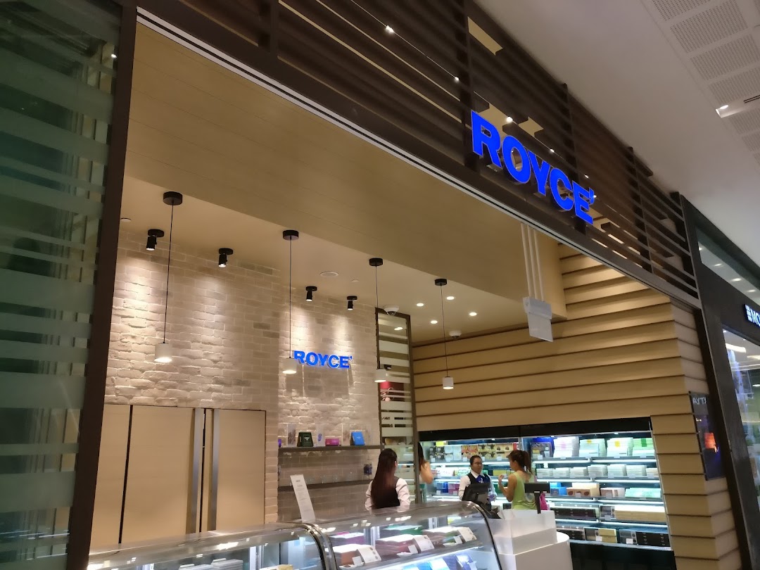 The Royce chocolate shop entrance features a modern design with a prominent blue logo and display cases.