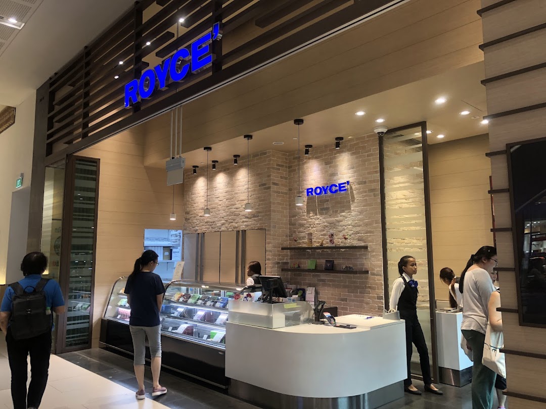 Interior view of Royce chocolate shop with customers browsing display cases and a service counter.