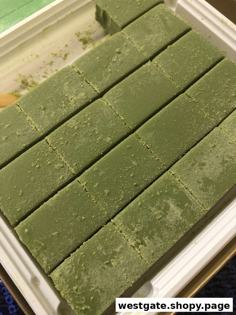 Close-up of green, matcha-dusted chocolates, likely Nama Chocolate, arranged in a white tray.