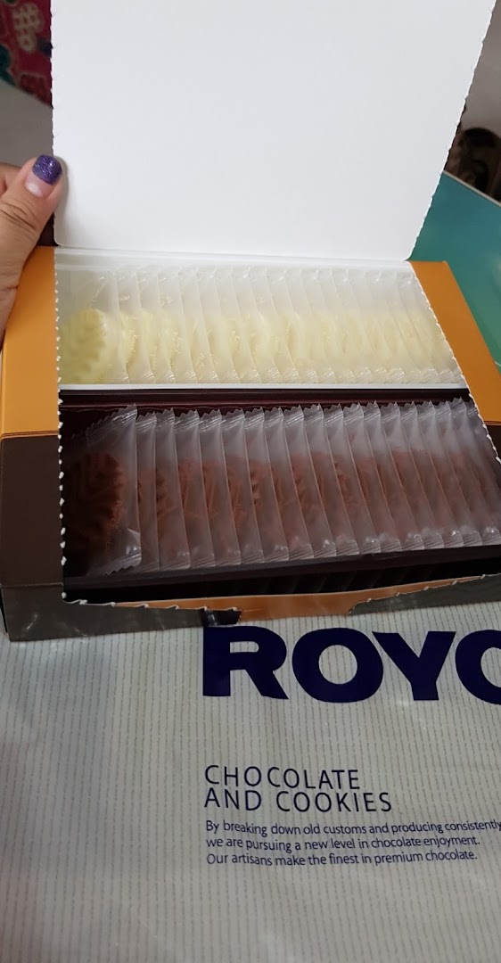 An open box of Royce chocolates and cookies, individually packaged in two varieties.