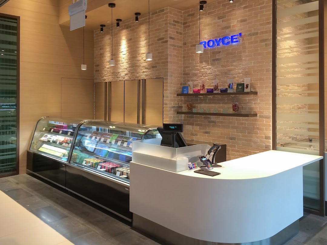 Interior view of Royce' chocolate shop featuring a display case, modern counter, and brick wall with branding.