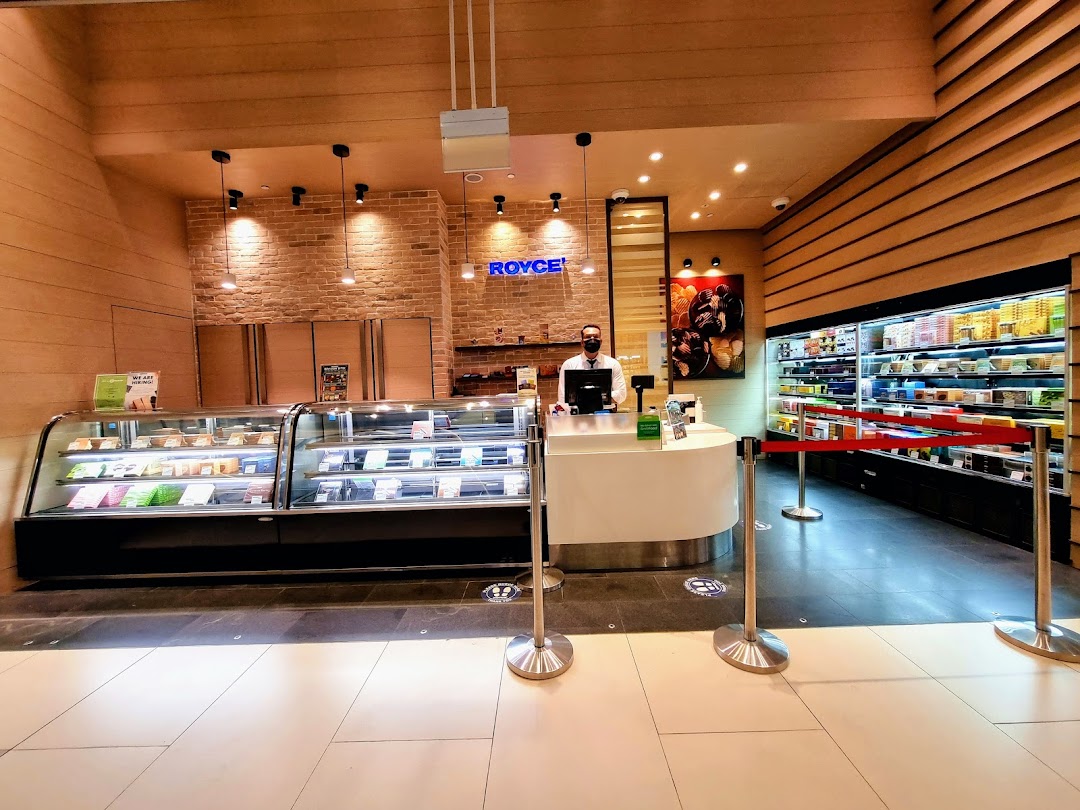 Interior view of Royce chocolate shop featuring display cases, a service counter, and a staff member.