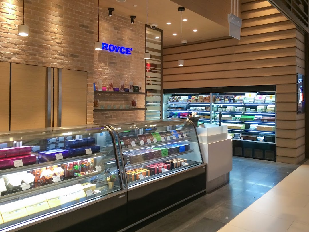 Interior view of Royce chocolate shop, showcasing display cases filled with various confections and a prominent brand sign.