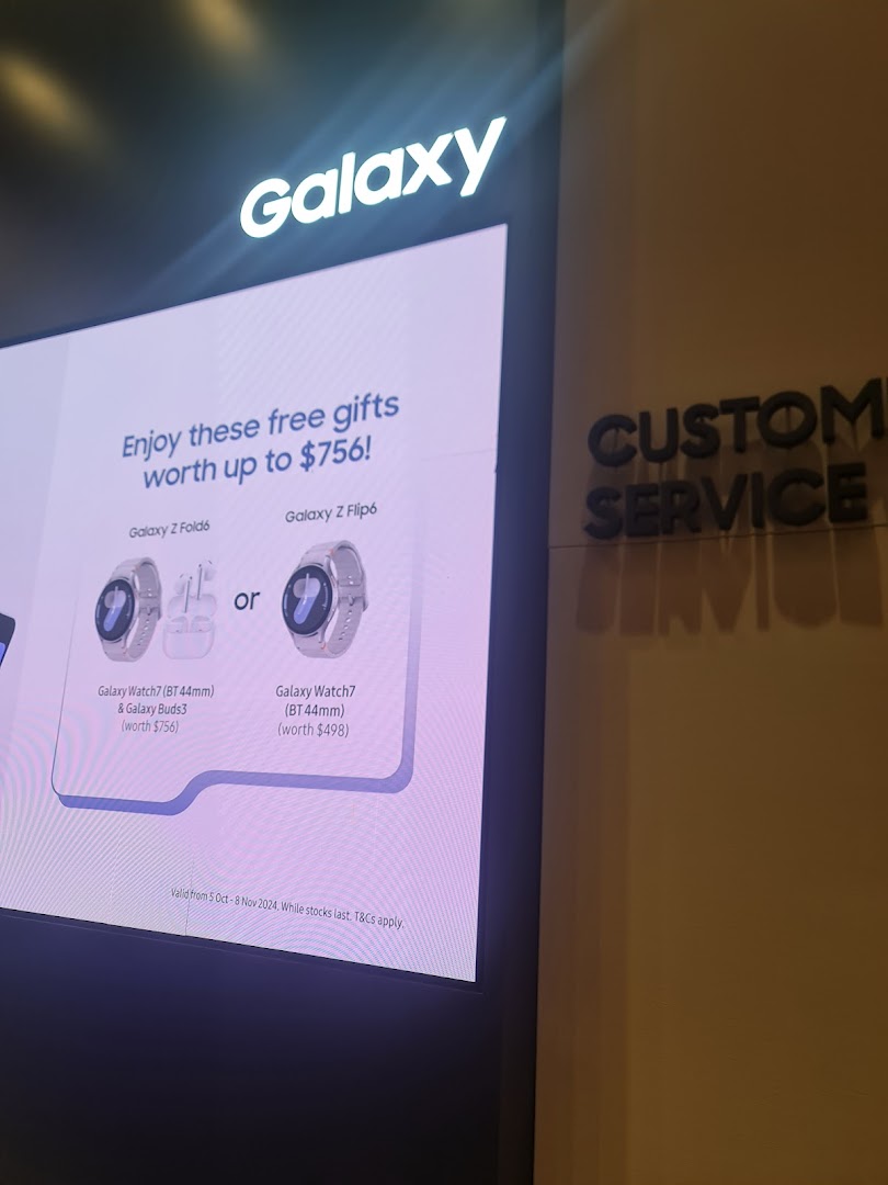 A Samsung Galaxy display showcasing free gifts with phone purchases, alongside a 'CUSTOMER SERVICE' sign.