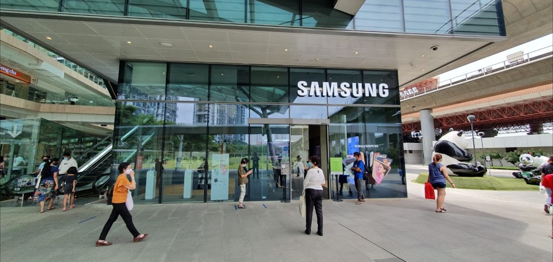 The modern glass facade of a Samsung Experience Store with people entering and exiting.