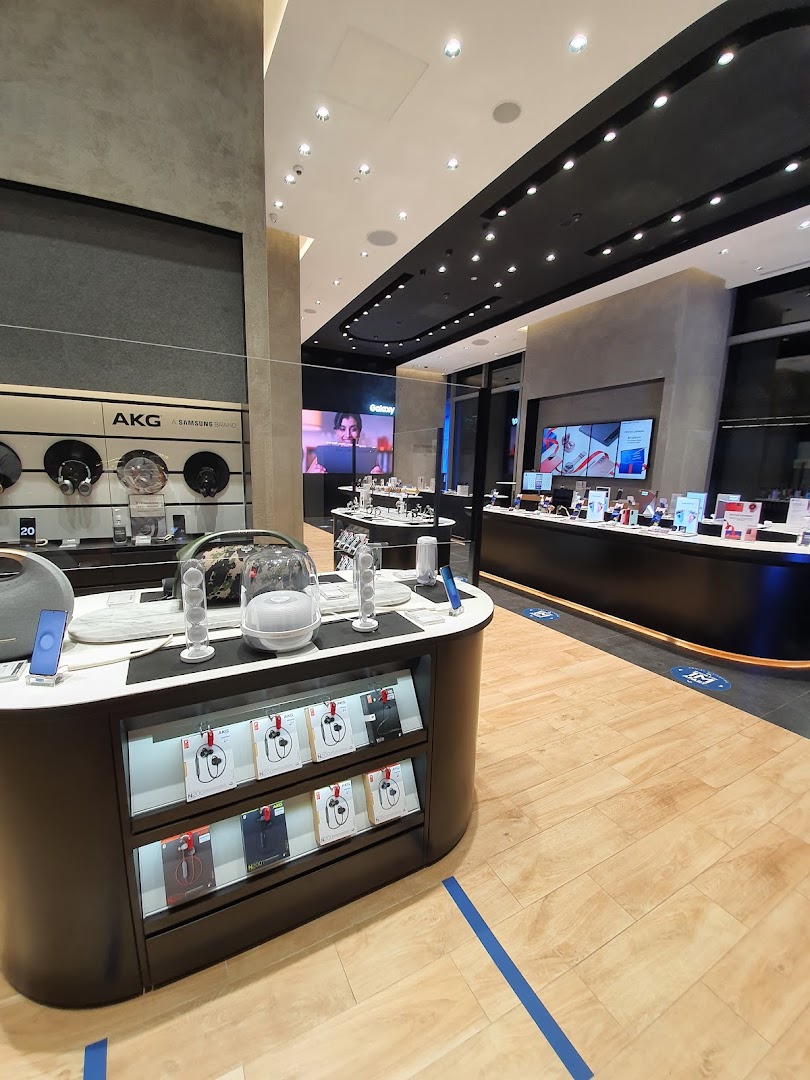 Interior view of a modern Samsung Experience Store showcasing various electronics, headphones, and interactive display screens.