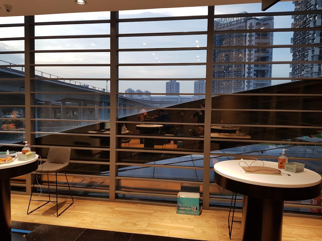 Interior view of a service centre with modern tables, chairs, and a large window overlooking the city.