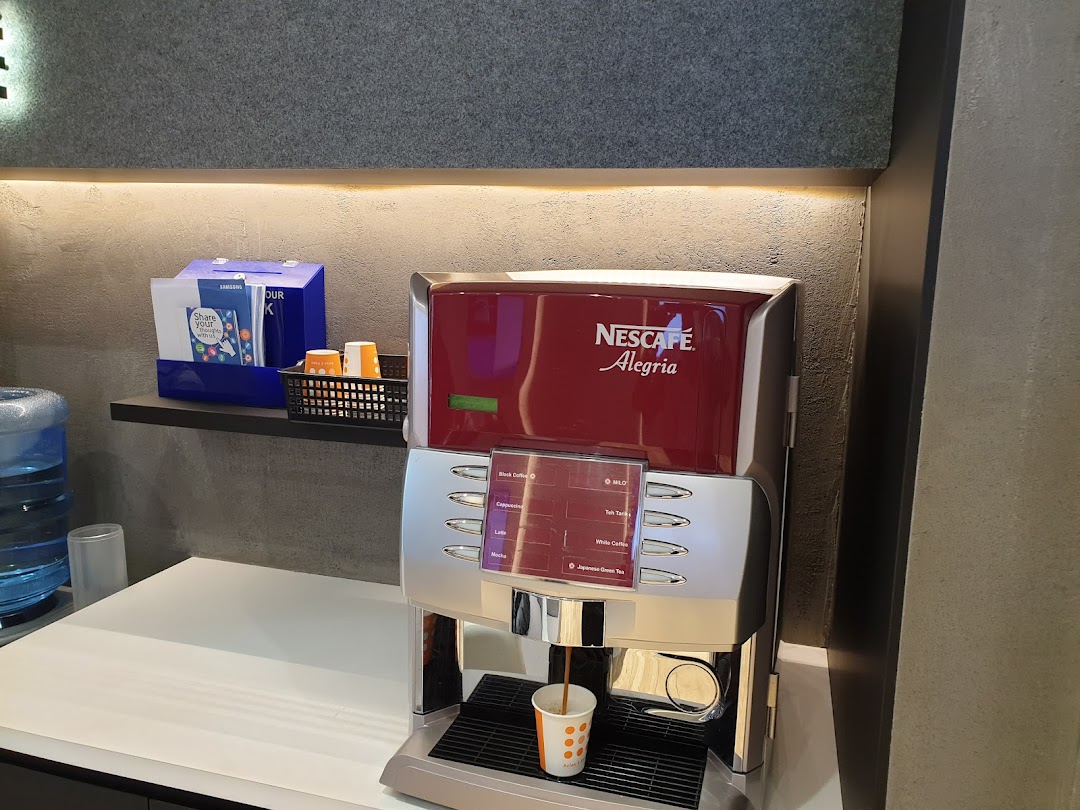 A Nescafe coffee machine and water dispenser in a modern service centre waiting area.