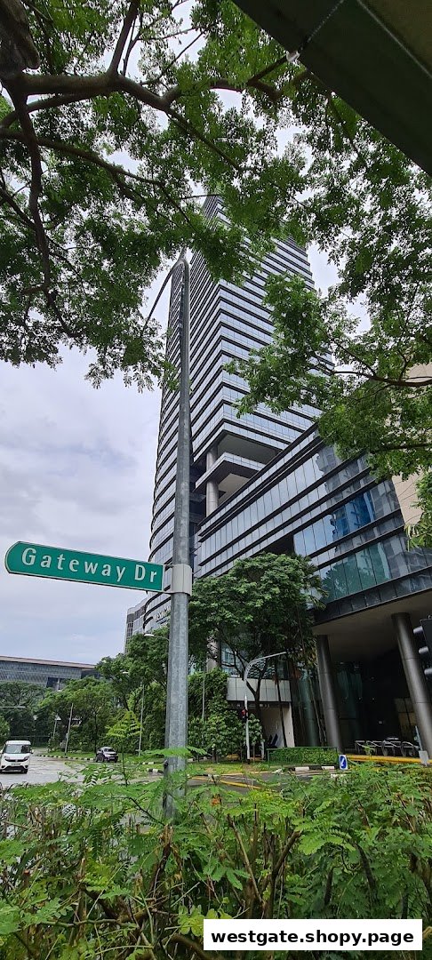 A tall modern building with a street sign for Gateway Drive, surrounded by lush greenery.